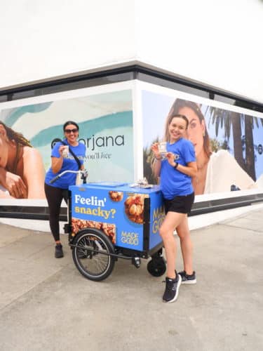 two woman in blue shirts showing snack samples