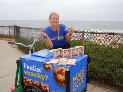 woman holding madegood bars next to the beach