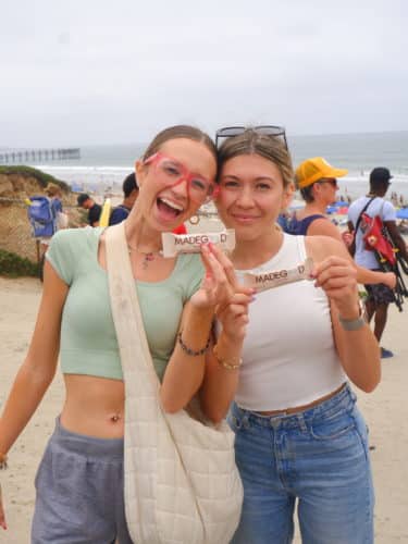 two woman smiling with madegood bards on the beach