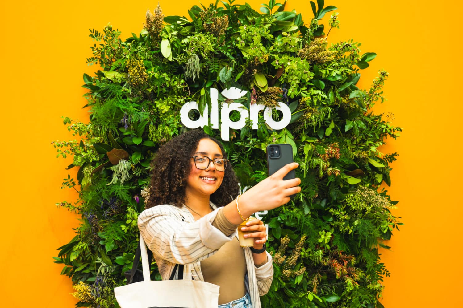 woman taking a selfie in front of a wall of greenery