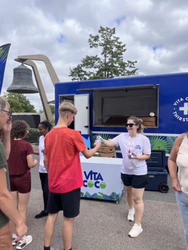 woman handing a man a coconut water carton