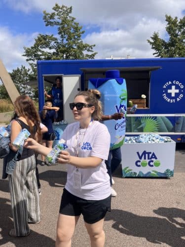 woman handing out cartons of coconut water