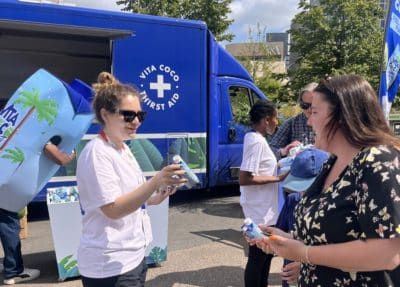 woman handing a woman a carton of coconut water